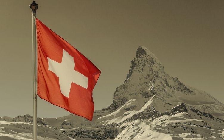 Bergspitze im Hintergrund mit Schweizer Flagge im Vodergrund