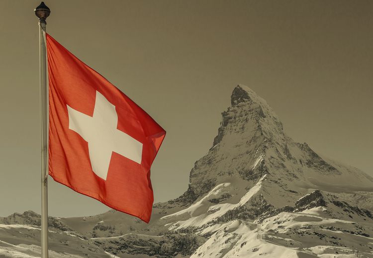 Bergspitze im Hintergrund mit Schweizer Flagge im Vodergrund